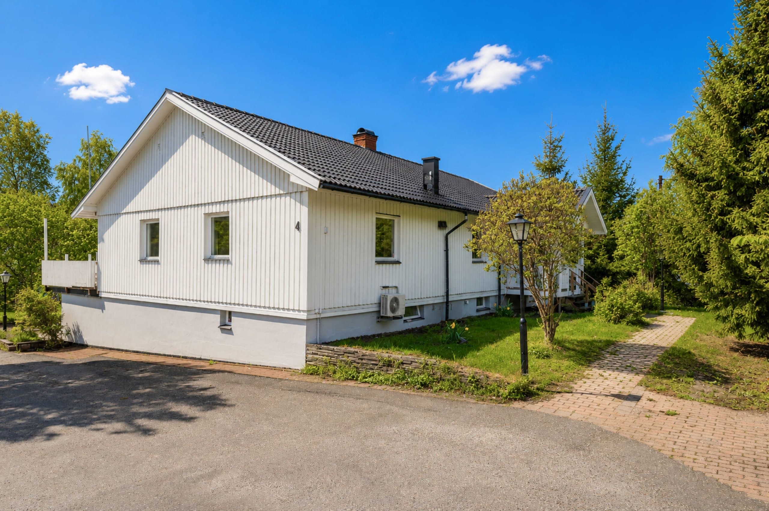 Charmant vitt fritidshus med modernt utseende, omgivet av grönska och naturlig miljö. Huset ligger på en lugn plats med gräsplan och väl underhållen trädgård.